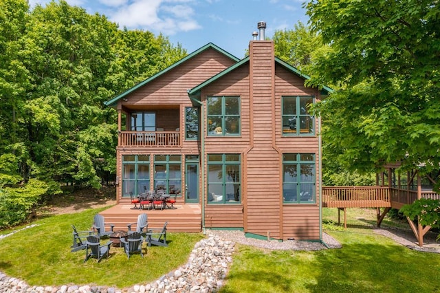 19260 Lakewood Dr, Deerwood Twp, MN 56444 - back of property featuring a balcony, an outdoor fire pit, a yard, a chimney, and a patio