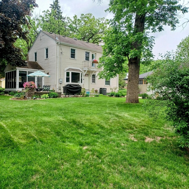 1308 73rd St, Richfield, MN 55423 - back of house featuring a sunroom, central AC unit, a chimney, and a yard