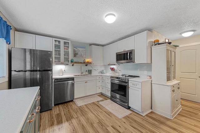 1858 Kennedy Ct, Northfield, MN 55057 - kitchen featuring stainless steel appliances, a sink, a textured ceiling, light wood-style floors, and light countertops