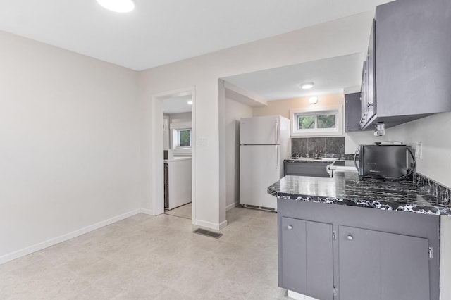 716 15th St NW, Bemidji, MN 56601 - kitchen featuring freestanding refrigerator, a peninsula, gray cabinets, a sink, and baseboards