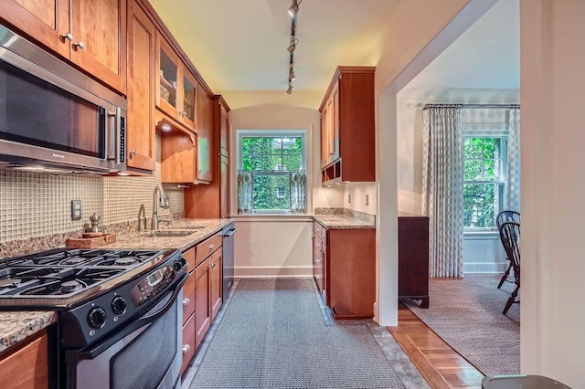 2517 Humboldt Ave S Unit 201, Minneapolis, MN 55405 - kitchen with appliances with stainless steel finishes, a sink, brown cabinets, baseboards, and light stone countertops