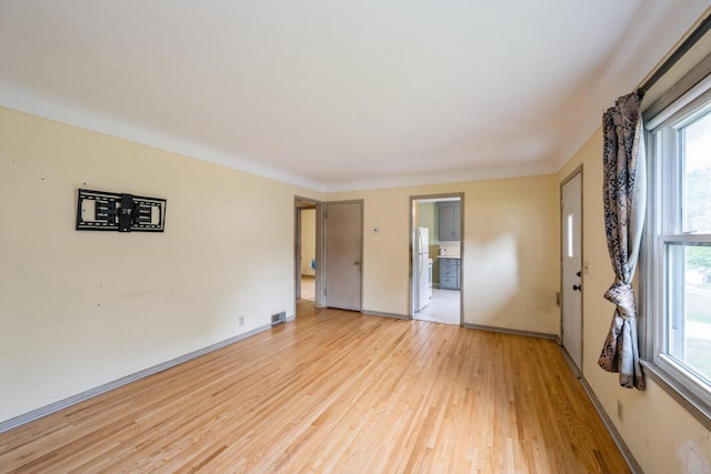 3425 Cleveland St NE, Minneapolis, MN 55418 - unfurnished bedroom featuring freestanding refrigerator, light wood-style flooring, multiple windows, and baseboards