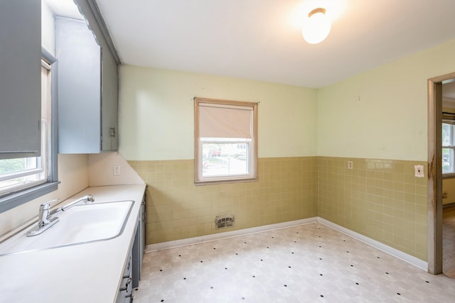 3425 Cleveland St NE, Minneapolis, MN 55418 - bathroom with tile walls, tile patterned floors, wainscoting, and a sink