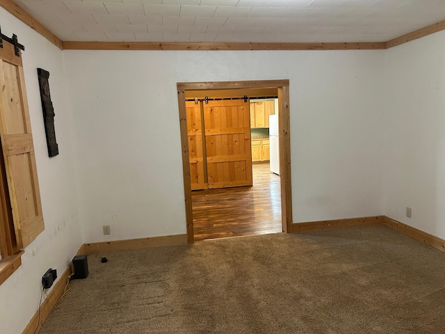 130 Tyler St, Tyler, MN 56178 - spare room with a barn door, carpet floors, and baseboards