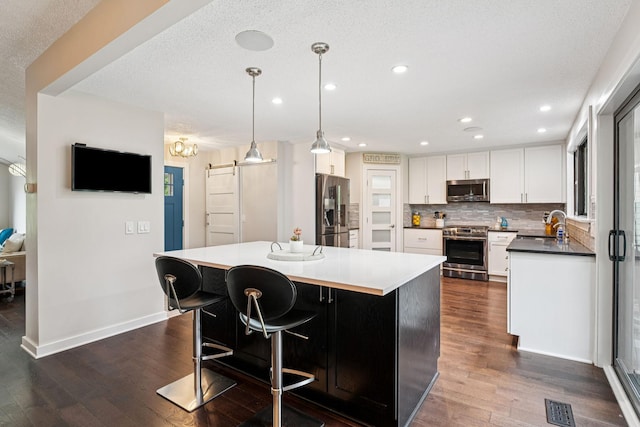 538 Silver Lake Rd NW, New Brighton, MN 55112 - kitchen with appliances with stainless steel finishes, white cabinets, dark wood-style flooring, a barn door, and baseboards