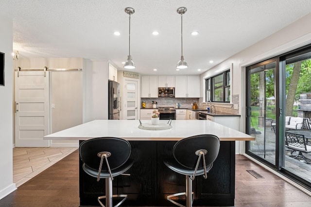 538 Silver Lake Rd NW, New Brighton, MN 55112 - kitchen with stainless steel appliances, dark wood-style floors, tasteful backsplash, healthy amount of natural light, and a textured ceiling