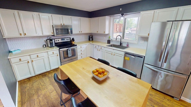 1715 Gateway Dr, Albert Lea, MN 56007 - kitchen with appliances with stainless steel finishes, a sink, wood finished floors, white cabinetry, and decorative backsplash