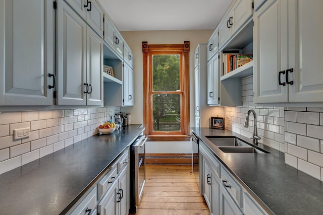605 7th Ave N, Saint Cloud, MN 56303 - kitchen featuring a sink, open shelves, dark countertops, light wood-style flooring, and tasteful backsplash