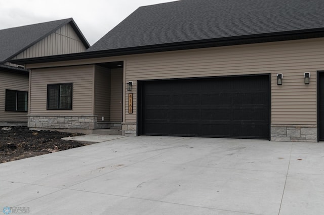 4174 Arthur Dr S, Fargo, ND 58104 - view of front facade with stone siding, driveway, a shingled roof, and board and batten siding