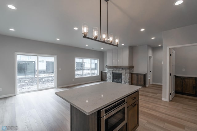 4174 Arthur Dr S, Fargo, ND 58104 - kitchen featuring stainless steel microwave, light wood-style floors, baseboards, recessed lighting, and a stone fireplace