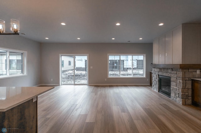 4174 Arthur Dr S, Fargo, ND 58104 - unfurnished living room featuring healthy amount of natural light, a fireplace, light wood-style floors, baseboards, and recessed lighting