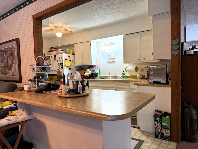 7780 Fawn Lake Dr NE, Stacy, MN 55079 - kitchen with a breakfast bar, a sink, freestanding refrigerator, ceiling fan, and white cabinets