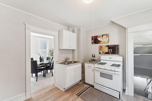 1404 Russell Ave N, Minneapolis, MN 55411 - kitchen featuring gas range gas stove, a sink, white cabinets, light wood-style flooring, and light countertops