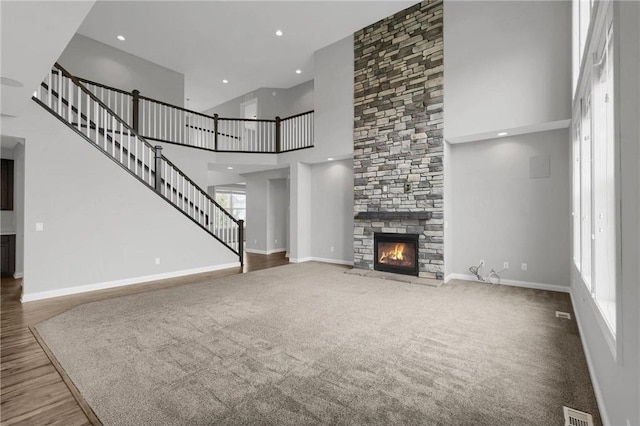 6919 156th St, Savage, MN 55378 - unfurnished living room featuring a towering ceiling, a stone fireplace, recessed lighting, and carpet