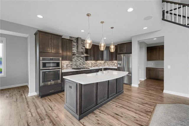 6919 156th St, Savage, MN 55378 - kitchen with appliances with stainless steel finishes, wall chimney exhaust hood, light wood-style floors, decorative backsplash, and recessed lighting