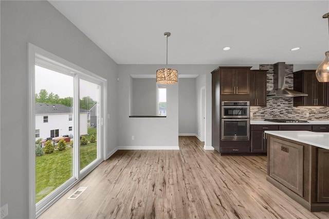 6919 156th St, Savage, MN 55378 - kitchen featuring wall chimney exhaust hood, appliances with stainless steel finishes, light countertops, light wood finished floors, and backsplash