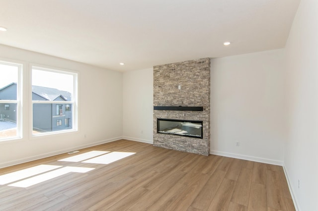 914 Milborne Ln NW, Rochester, MN 55901 - unfurnished living room featuring light wood-style flooring, baseboards, a stone fireplace, and recessed lighting