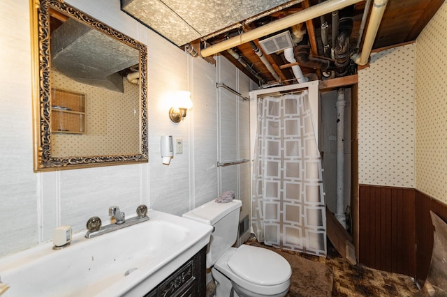 2208 17th Ave NW, Rochester, MN 55901 - bathroom with wallpapered walls, toilet, vanity, and a wainscoted wall