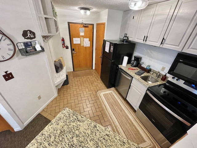 128 Bridge Run Ln Unit B, Lutsen Twp, MN 55612 - kitchen with black appliances, a sink, white cabinets, a textured ceiling, and decorative light fixtures