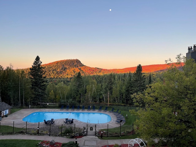 128 Bridge Run Ln Unit B, Lutsen Twp, MN 55612 - pool at dusk with a community pool, a view of trees, a patio, and a mountain view