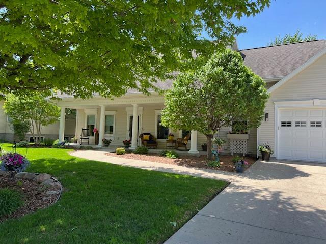 1120 Southridge Rd, New Ulm, MN 56073 - obstructed view of property featuring a porch, concrete driveway, a front lawn, and an attached garage
