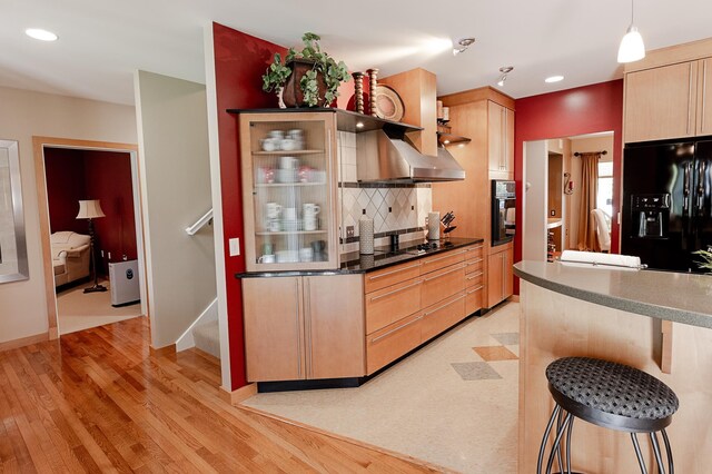 1120 Southridge Rd, New Ulm, MN 56073 - kitchen featuring black appliances, wall chimney exhaust hood, light brown cabinetry, tasteful backsplash, and a kitchen breakfast bar