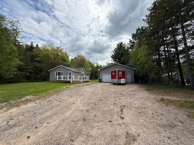 11966 Lindquist Rd, Hibbing, MN 55746 - view of front facade featuring dirt driveway, an outdoor structure, a detached garage, a deck, and a front lawn