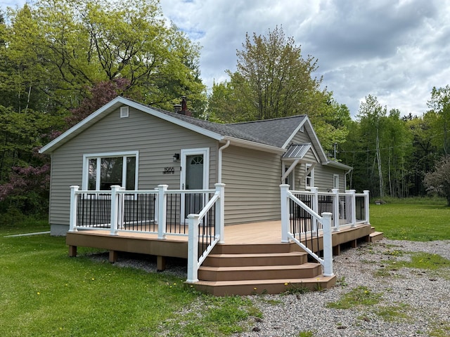 11966 Lindquist Rd, Hibbing, MN 55746 - view of front of property featuring a deck, a shingled roof, a front lawn, and a forest view
