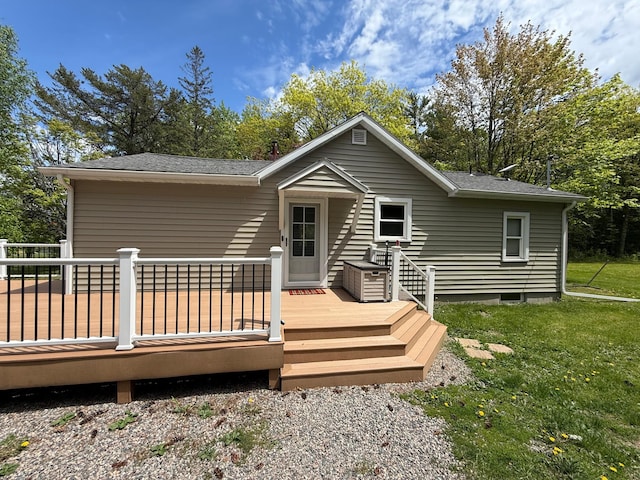 11966 Lindquist Rd, Hibbing, MN 55746 - back of property featuring a lawn, a shingled roof, a deck, and view of scattered trees