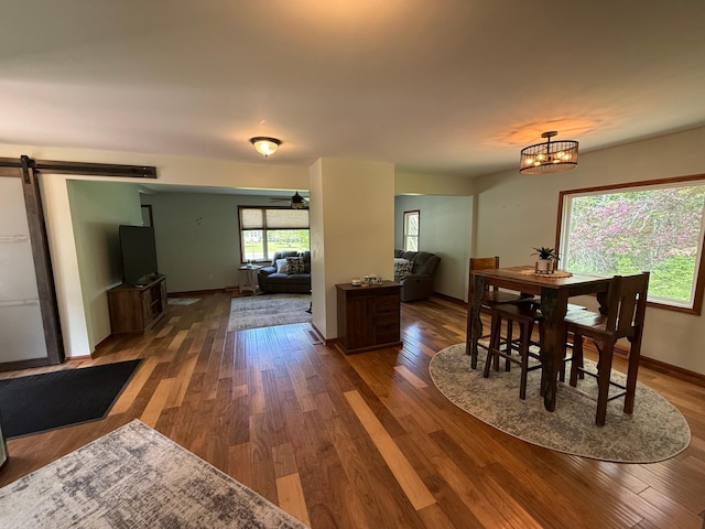 11966 Lindquist Rd, Hibbing, MN 55746 - dining space with a barn door, wood finished floors, baseboards, and a chandelier