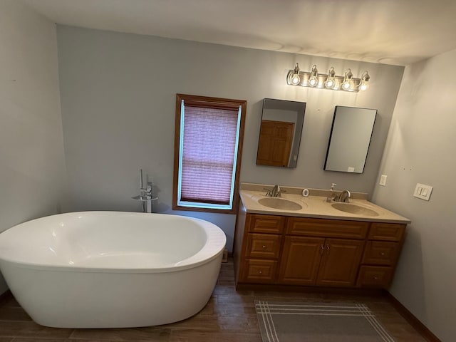 11966 Lindquist Rd, Hibbing, MN 55746 - bathroom featuring double vanity, a soaking tub, wood finished floors, and baseboards