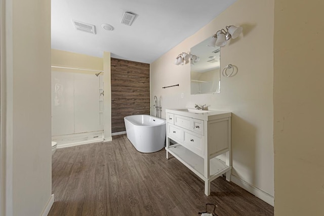 517 1st Ave NW, Winnebago, MN 56098 - bathroom featuring vanity, wood finished floors, walk in shower, a soaking tub, and toilet