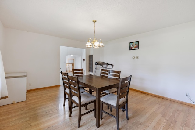 8187 230th St E, Faribault, MN 55021 - dining space featuring light wood finished floors, a chandelier, baseboards, and arched walkways