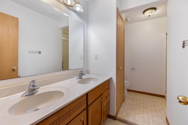 8187 230th St E, Faribault, MN 55021 - bathroom featuring toilet, double vanity, and baseboards