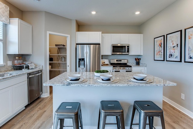 1025 Shoreview Dr, Jordan, MN 55352 - kitchen featuring appliances with stainless steel finishes, a breakfast bar area, light wood-style floors, white cabinetry, and recessed lighting