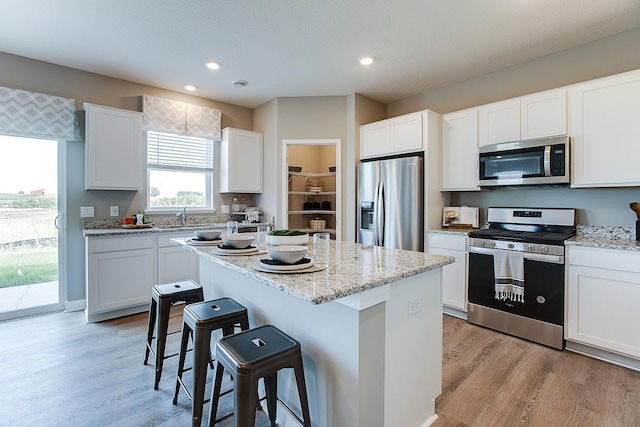 1025 Shoreview Dr, Jordan, MN 55352 - kitchen with appliances with stainless steel finishes, a kitchen breakfast bar, light wood-style flooring, a center island, and white cabinetry