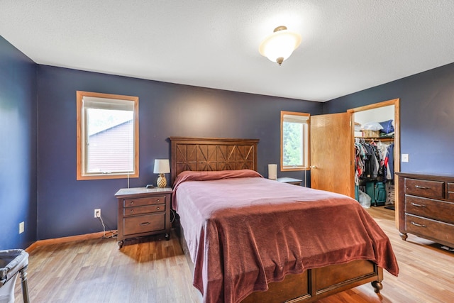 810 7th Ave N, Sauk Rapids, MN 56379 - bedroom with light wood-style floors, a spacious closet, a closet, baseboards, and a textured ceiling