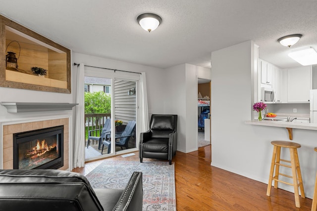 16047 72nd St NE, Otsego, MN 55330 - living area featuring a textured ceiling, light wood-style flooring, baseboards, and a tiled fireplace