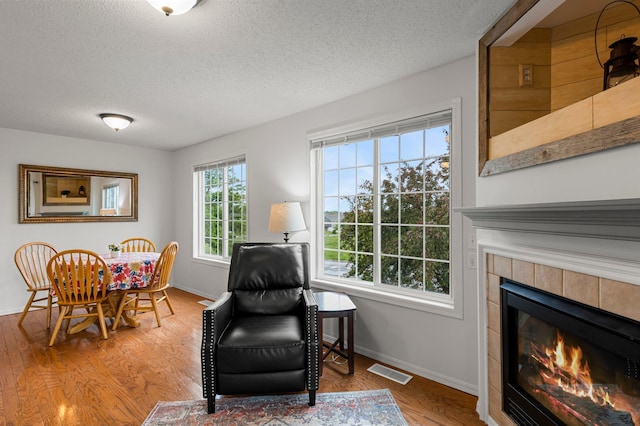 16047 72nd St NE, Otsego, MN 55330 - sitting room featuring a textured ceiling, a tiled fireplace, baseboards, and wood finished floors