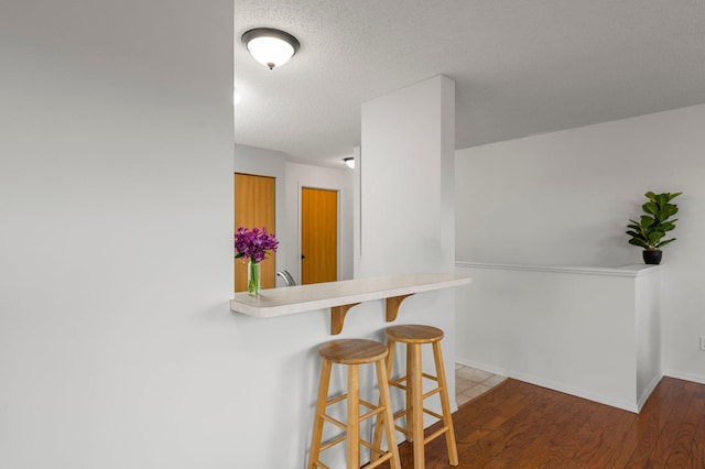 16047 72nd St NE, Otsego, MN 55330 - kitchen featuring a kitchen breakfast bar, light countertops, wood finished floors, baseboards, and a textured ceiling