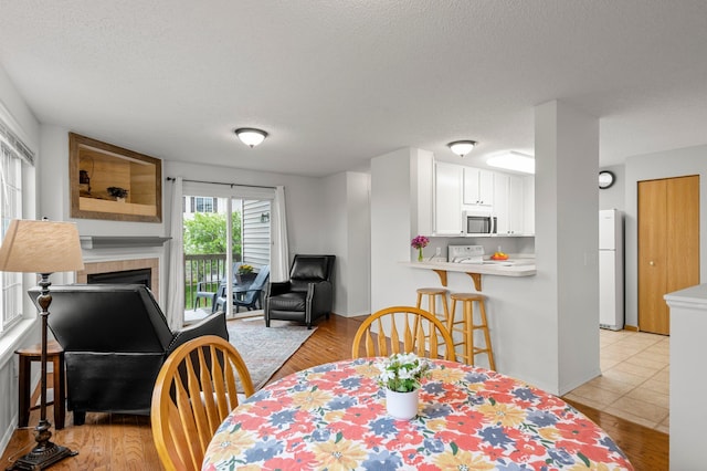 16047 72nd St NE, Otsego, MN 55330 - dining space with a tile fireplace, light wood-style floors, and a textured ceiling