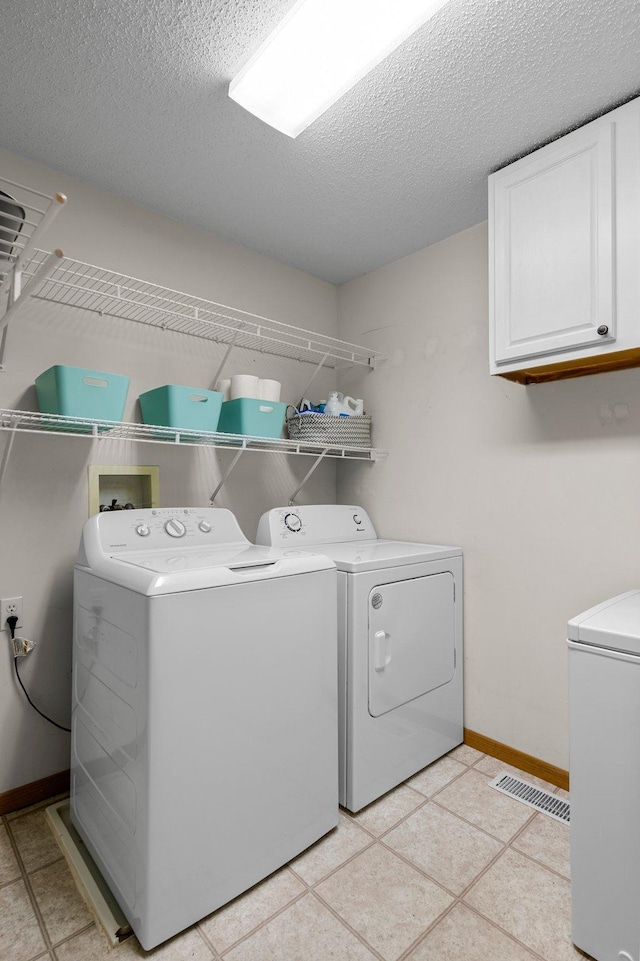 16047 72nd St NE, Otsego, MN 55330 - laundry area featuring separate washer and dryer, cabinet space, baseboards, a textured ceiling, and light tile patterned floors