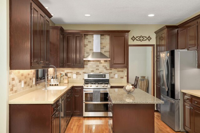 16976 81st Ave N, Maple Grove, MN 55311 - kitchen featuring appliances with stainless steel finishes, wall chimney range hood, a sink, light wood finished floors, and recessed lighting