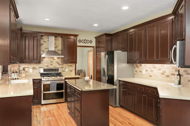 16976 81st Ave N, Maple Grove, MN 55311 - kitchen featuring stainless steel appliances, wall chimney exhaust hood, a sink, decorative backsplash, and light wood finished floors