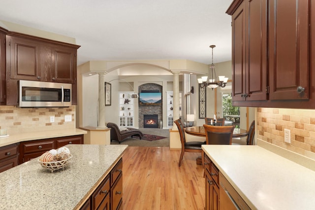 16976 81st Ave N, Maple Grove, MN 55311 - kitchen featuring stainless steel microwave, ornate columns, a fireplace, and light wood-type flooring