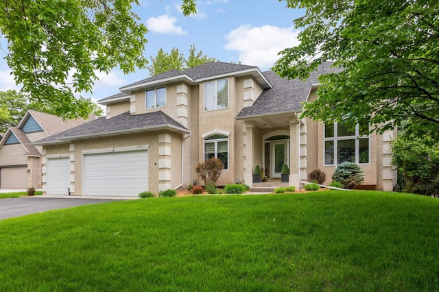 16976 81st Ave N, Maple Grove, MN 55311 - view of front facade with a front yard, roof with shingles, driveway, a garage, and stucco siding