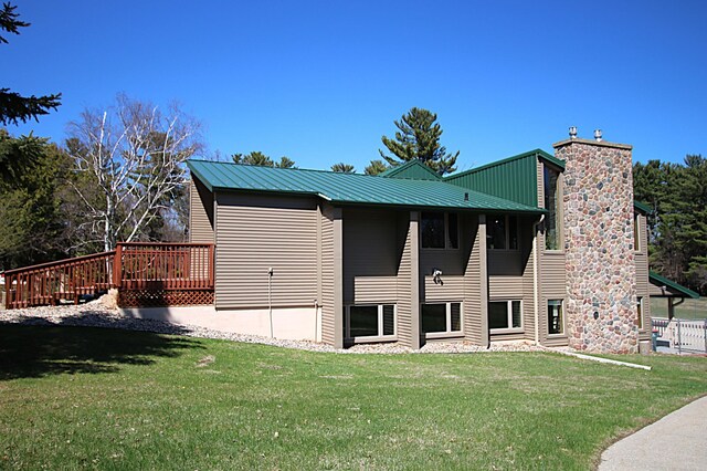 39817 Osage Dr, Browerville, MN 56438 - back of property featuring a chimney, a lawn, a wooden deck, and metal roof