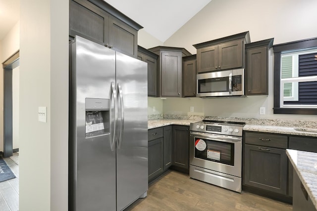 7833 Ava Trl, Inver Grove Heights, MN 55077 - kitchen featuring stainless steel appliances, vaulted ceiling, dark wood-style flooring, light stone countertops, and dark brown cabinetry