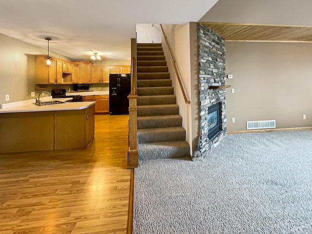 2002 Willow Cir, Centerville, MN 55038 - kitchen with black refrigerator with ice dispenser, stove, light countertops, a peninsula, and light wood-type flooring