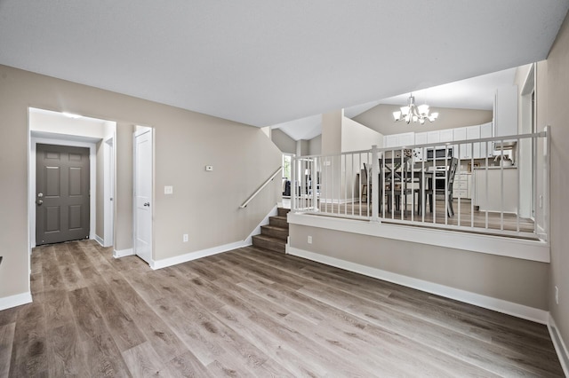 3825 122nd Ave NW, Coon Rapids, MN 55433 - spare room with a chandelier, light wood-style floors, baseboards, stairs, and lofted ceiling